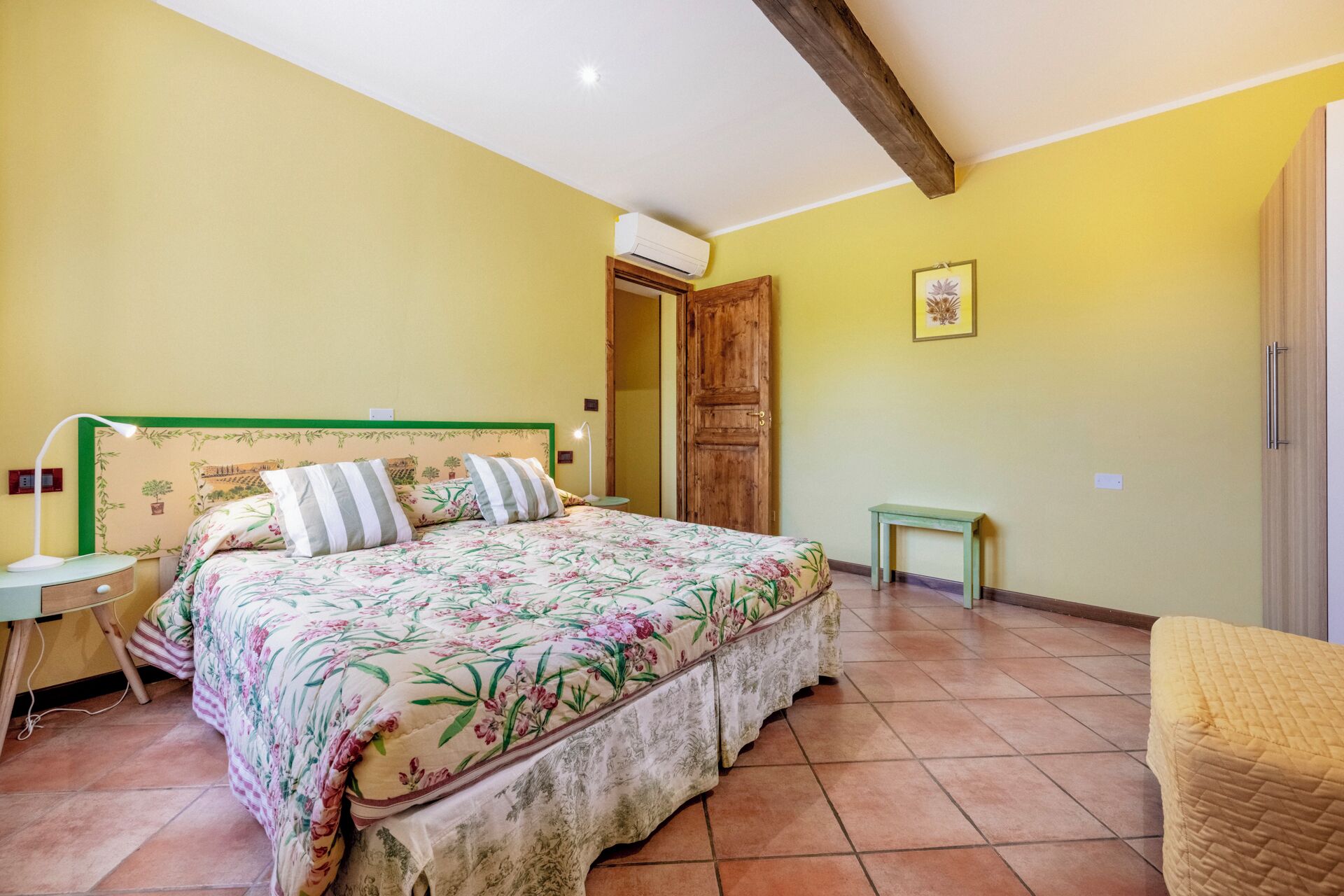 Ein Schlafzimmer mit einem Bett, Nachttischen, einer Holztür und einem kleinen Tisch.