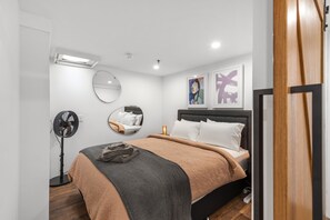 Relax in this serene bedroom with a neatly made bed, round mirror, and framed artworks.