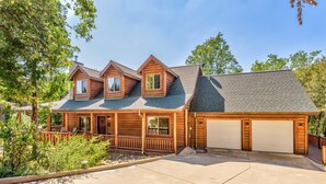 A log cabin with a porch, two attached lofts, and a garage.