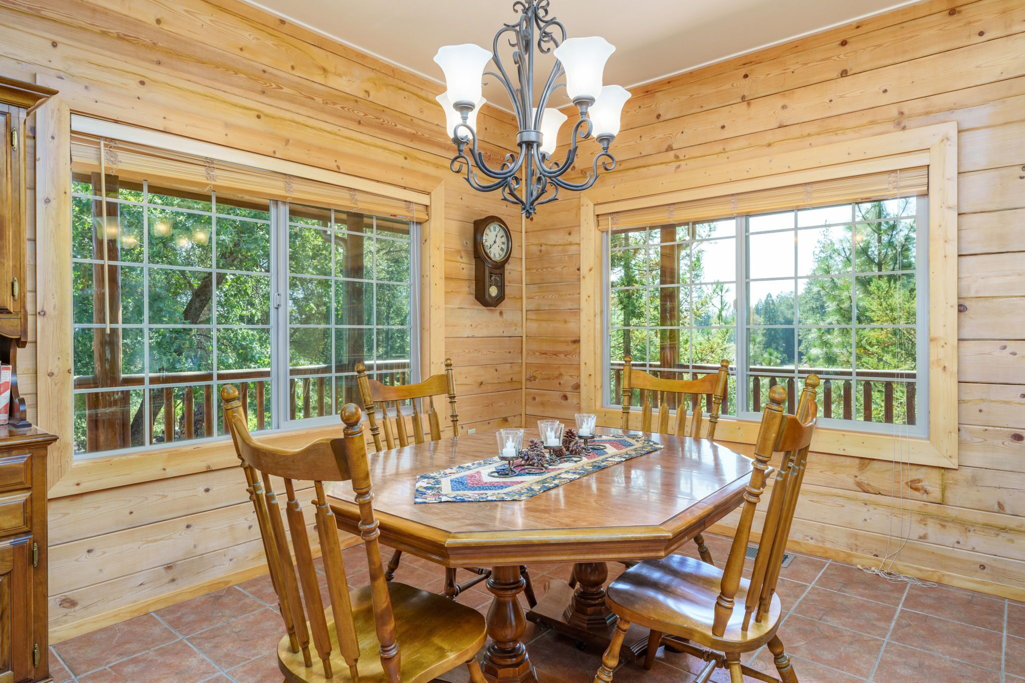 Ein Esszimmer mit Holzwandverkleidung, einem großen Tisch, Stühlen und einer Deckenleuchte.