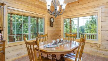 Ein Esszimmer mit Holzwandverkleidung, einem großen Tisch, Stühlen und einer Deckenleuchte.