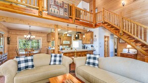 A cozy cabin interior with a wooden staircase, a dining area, and a kitchen.
