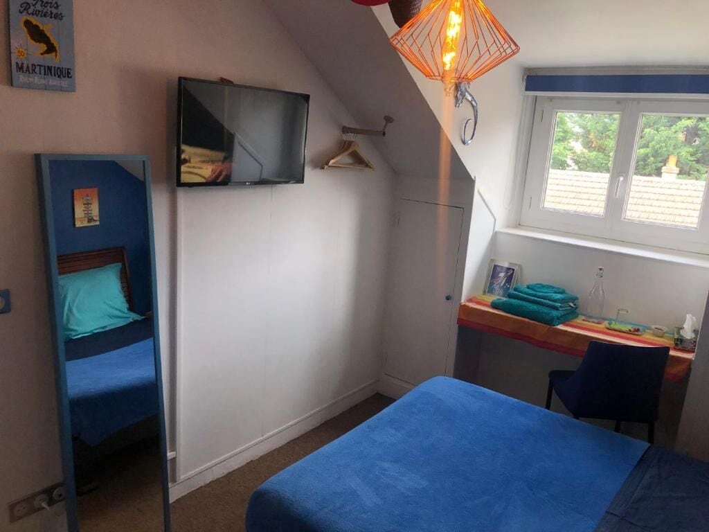 Een slaapkamer met een stapelbed, een bureau en een raam met uitzicht op groen.