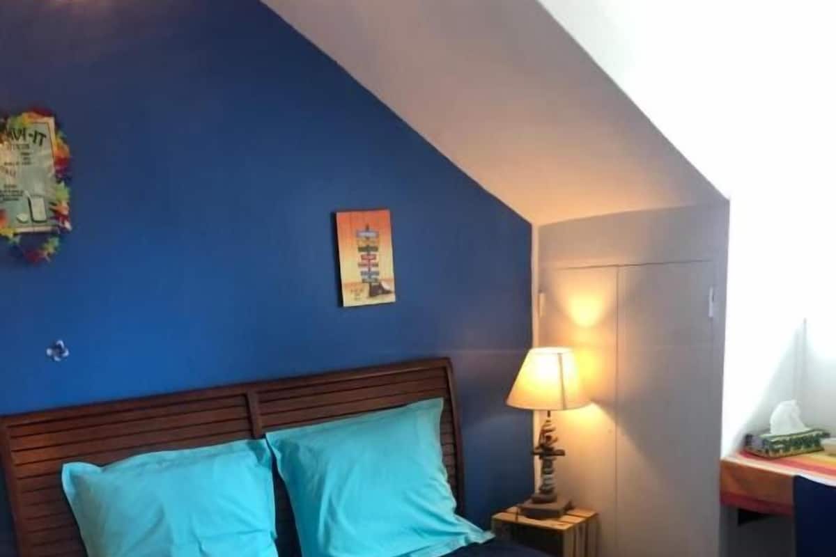 A bedroom with a bed, a nightstand, a desk, and a lamp.