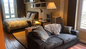 A bedroom with a bed, a desk with a computer, a lamp, and a couch. - Villa Eugénie, Gîtes & Chambres d'Hôtes  (Melun)