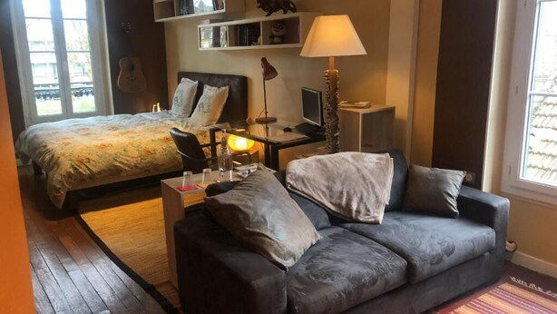 Ein Schlafzimmer mit einem Bett, einem Schreibtisch mit Computer, einer Lampe und einem Sofa.