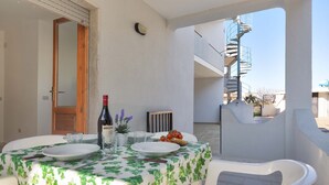 A dining area with a table set for two, a bottle of wine, and a potted plant. - 2244 Residence Anna - Appartamento Sarago (Taviano)