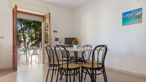 A dining area with a round table and four chairs, a small potted plant, and a painting on the wall. - 2244 Residence Anna - Appartamento Sarago (Taviano)