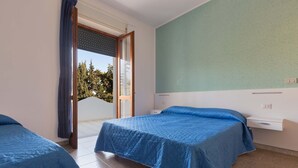 A room with two beds, a window with curtains, a white bedside table, and a green wall. - 2246 Residence Anna - Appartamento Orata (Taviano)