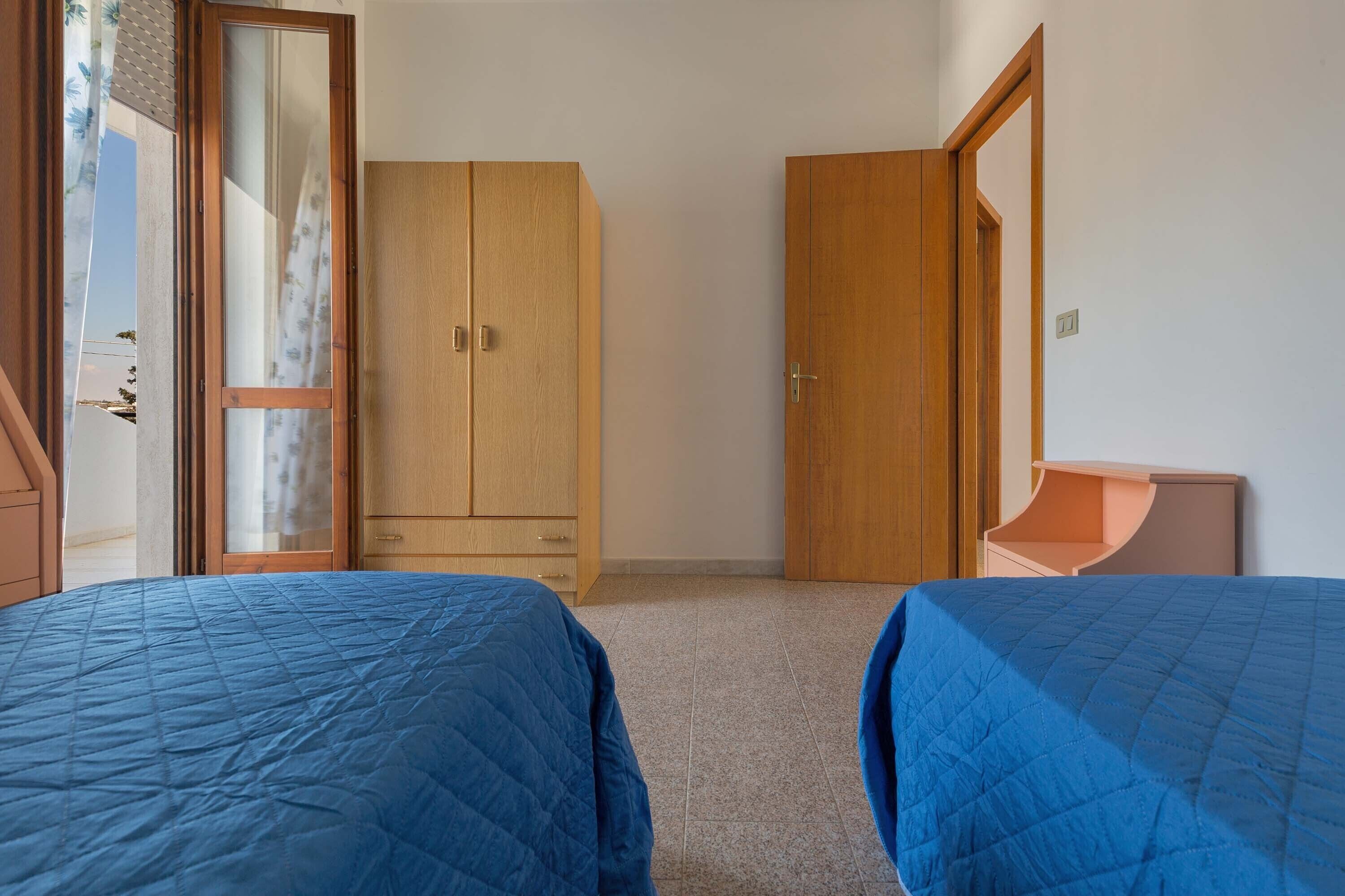 Une chambre avec deux lits, des armoires en bois et une petite table de chevet.