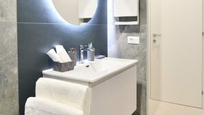 A modern bathroom with a white vanity, a round mirror, and a towel rack. - SIMONA's apartment in Rome a stone's throw from St. Peter's (ROMA)