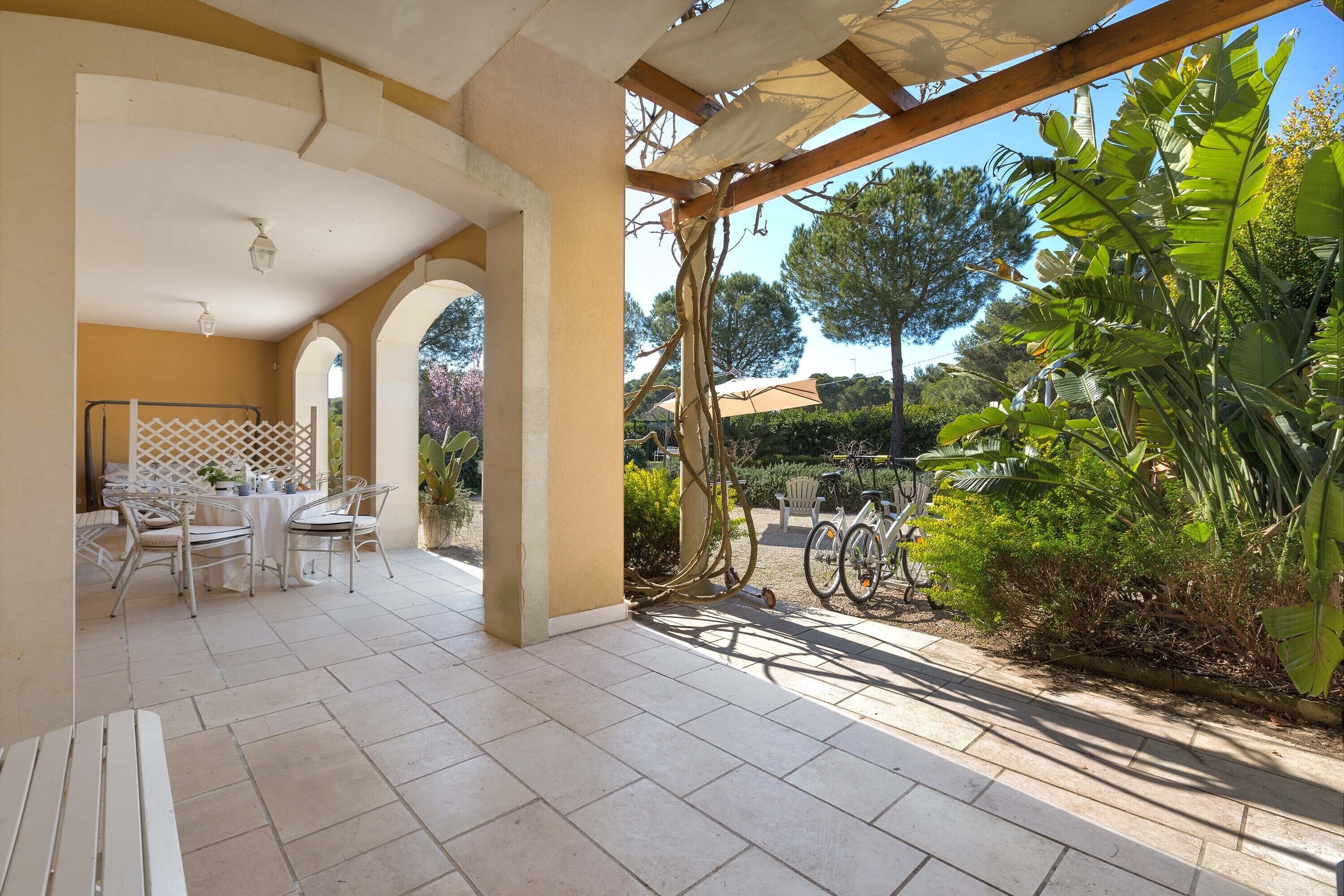 An outdoor patio area with a table and chairs, a pergola, and bicycles.