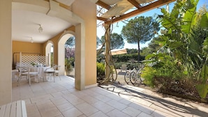 Un espacio al aire libre con patio, una mesa, sillas, una pérgola y bicicletas.