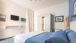 Ein Schlafzimmer mit Bett, Fernseher, Kleiderschrank und einem Regal mit Bildern.