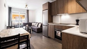 A modern kitchen with wooden cabinets, a built-in oven, and a dining area with a table and chairs.
