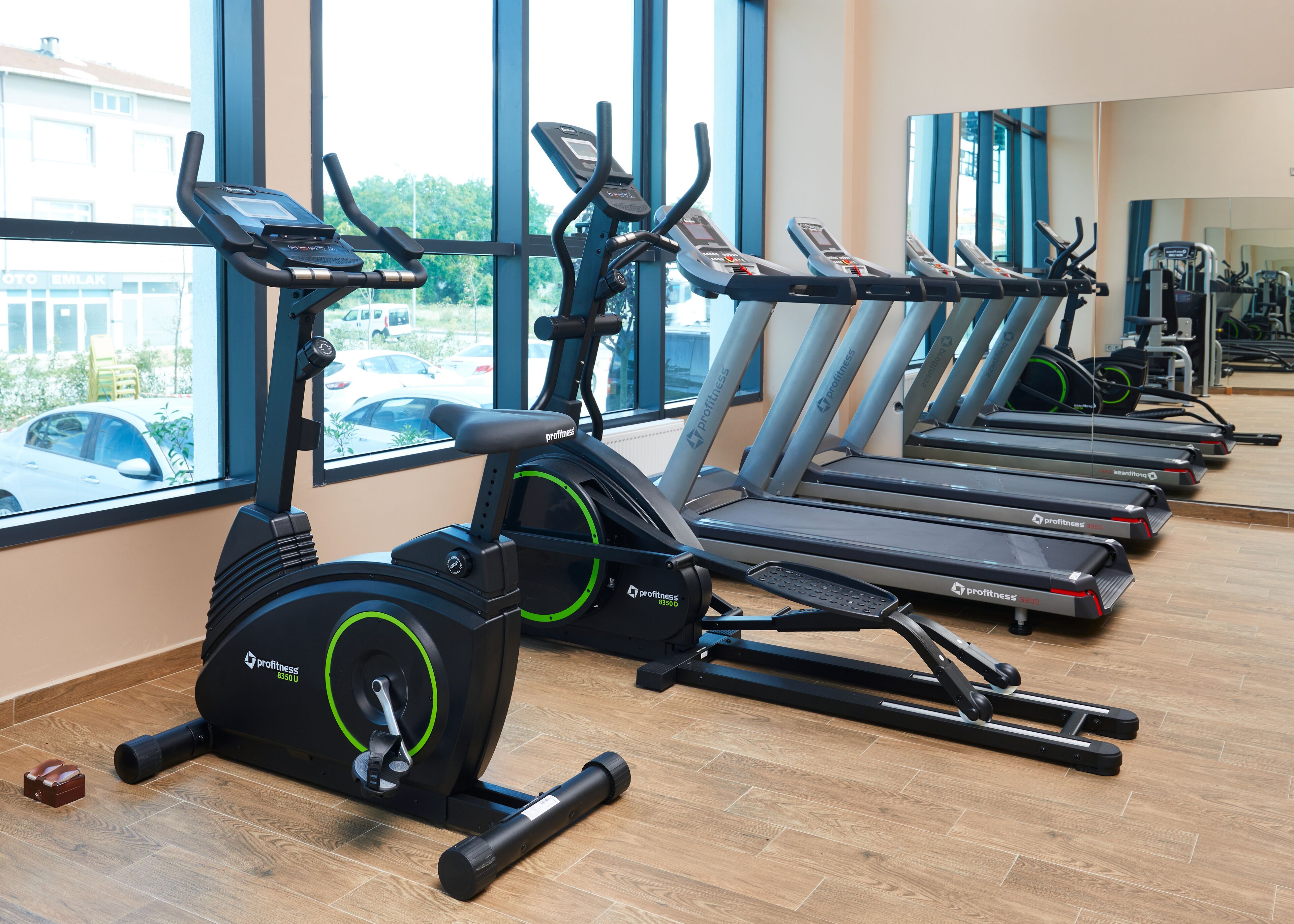 Una palestra con diverse tapis roulant e cyclette, ampie finestre e vista all'esterno.