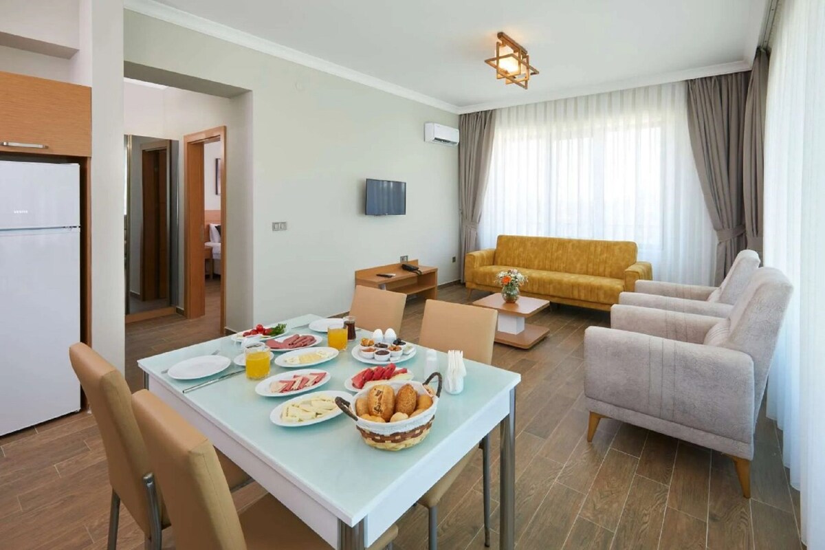 Ein Essbereich mit einem für das Frühstück gedeckten Tisch, einer Couch und einem Fernseher im Wohnzimmer.