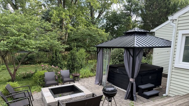 A patio area with a grill, seating, and a gazebo.