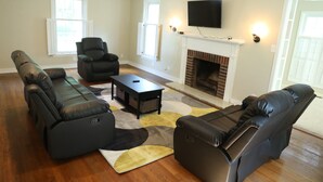 A living room with a sectional sofa, a recliner, a coffee table, and a fireplace.