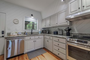 A kitchen with white cabinets, a stainless steel dishwasher, a microwave, and an oven.