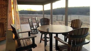 A covered patio with a round table and chairs, a heater, and a view of a field. - Brazos River Ranch near PK & Rocker B Ranch  (Mineral Wells)