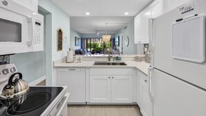 Una cocina moderna con armarios blancos, horno empotrado, microondas y refrigerador.