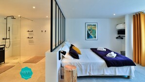 Una habitación de hotel moderna con cama, zona de ducha y un cartel en la pared.