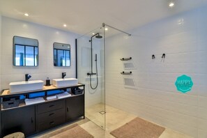 A modern bathroom with two sinks, a glass shower enclosure, and a towel rack.