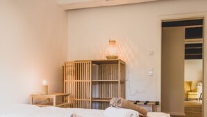 Ein Hotelzimmer mit einem Bett, einem Nachttisch aus Holz mit einer Lampe, einer Holzregaleinheit und einem Handtuch auf dem Bett.