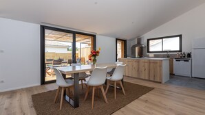 Eine moderne Küche mit Essbereich, Holzschränken und einem großen Fenster.