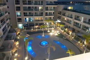 A multi-level building with a central courtyard featuring a circular water feature and surrounding greenery.