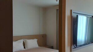 A hotel room with a bed, pillows, a TV mounted on the wall, and a window. - Brisas do Lago - apartamento 5 (Brasília)