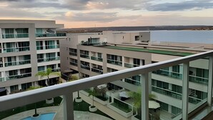 A modern building with multiple floors, large windows, and a pool area. - Brisas do Lago - apartamento 5 (Brasília)