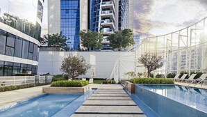 A modern pool area with clear blue water, steps leading to the pool, and lounge chairs. - LUX The Pad Executive Suite 2 (Dubai)