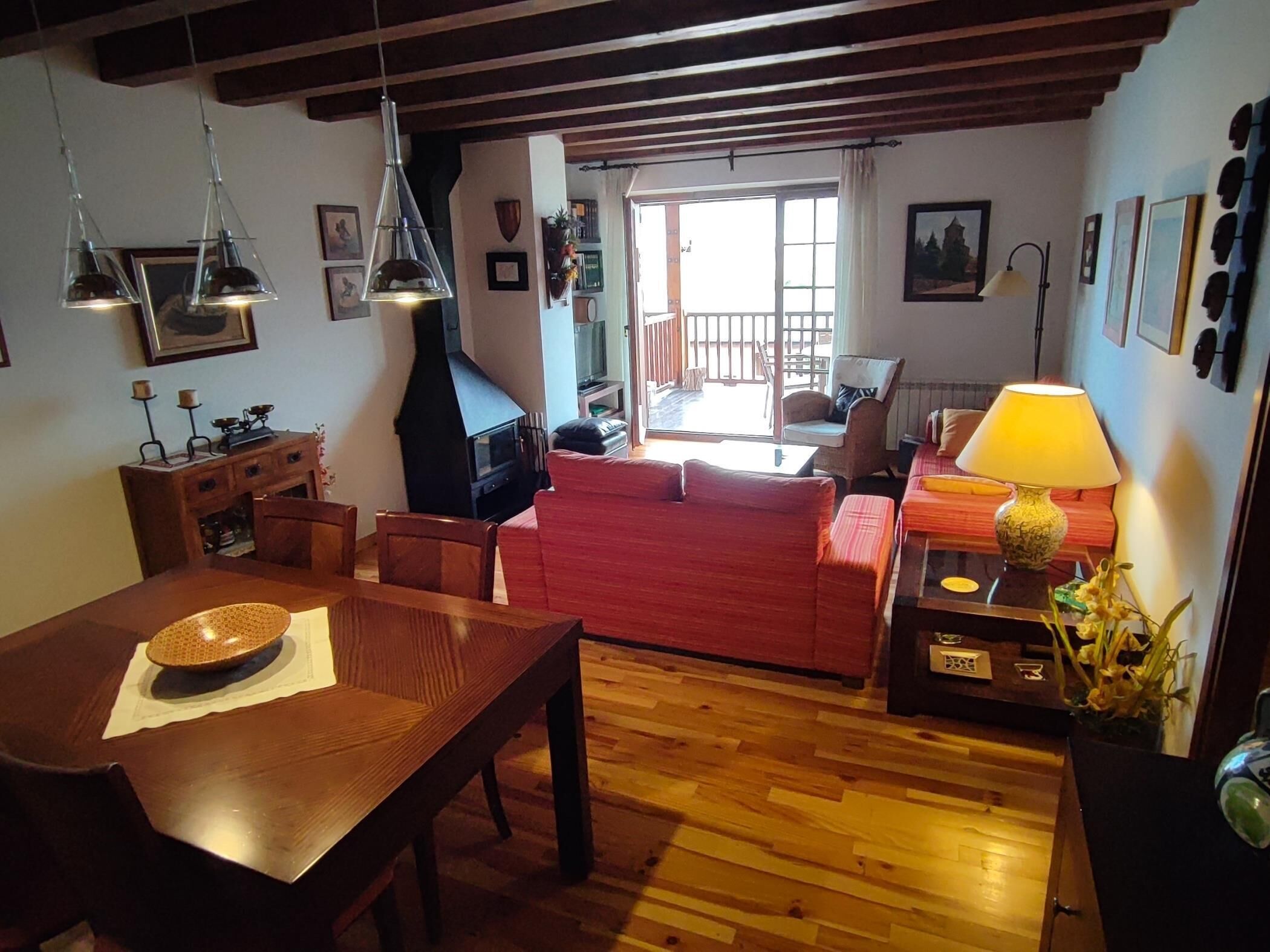Un salon chaleureux avec une table à manger en bois, un canapé rouge et une cheminée.