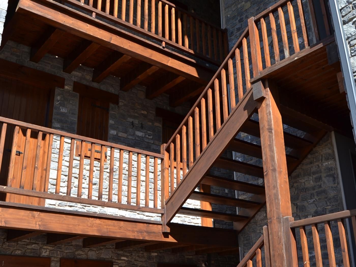 A multi-level wooden staircase with stone walls.
