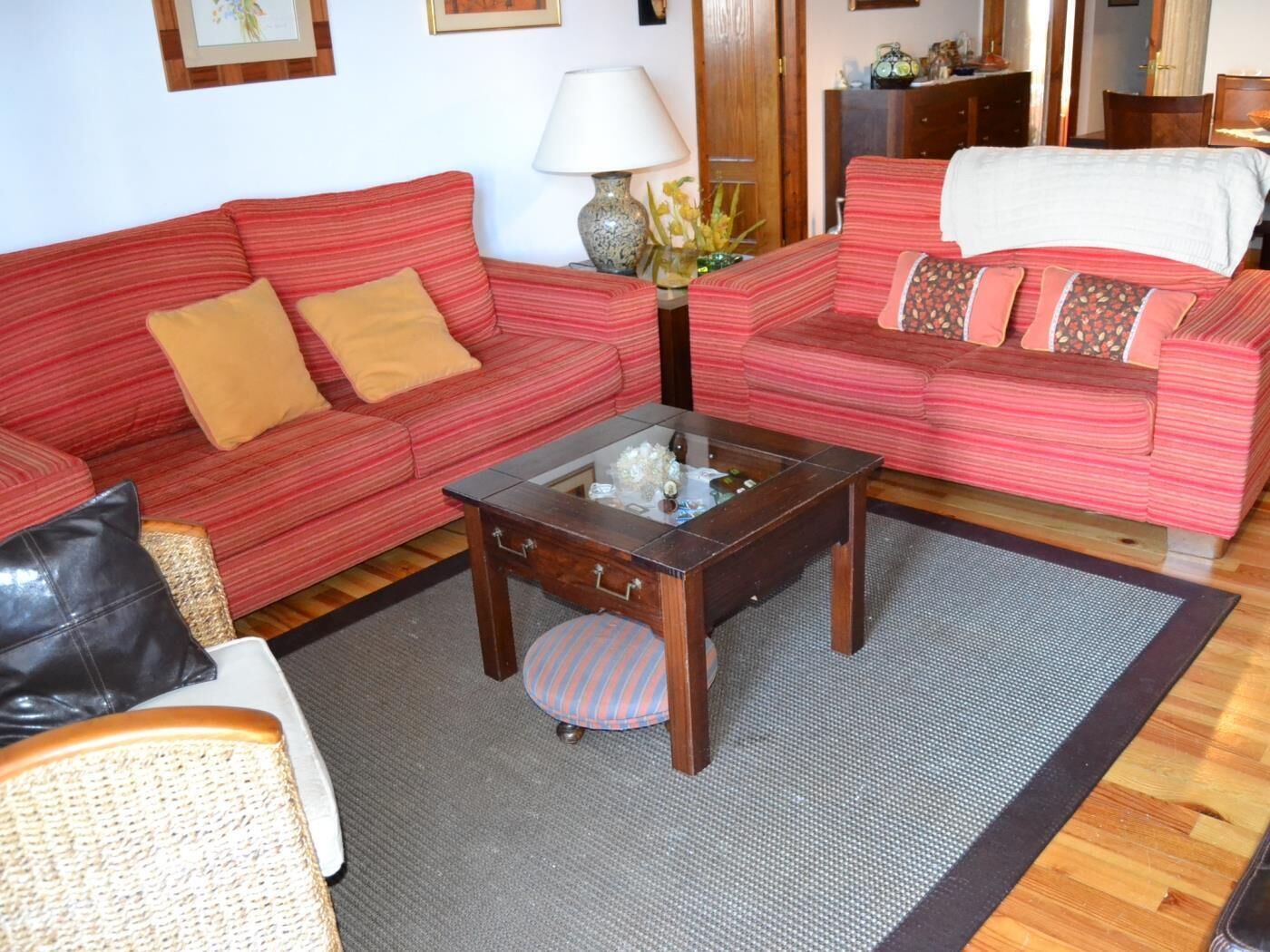 A living room with two red-striped sofas, a glass coffee table, and a lamp.
