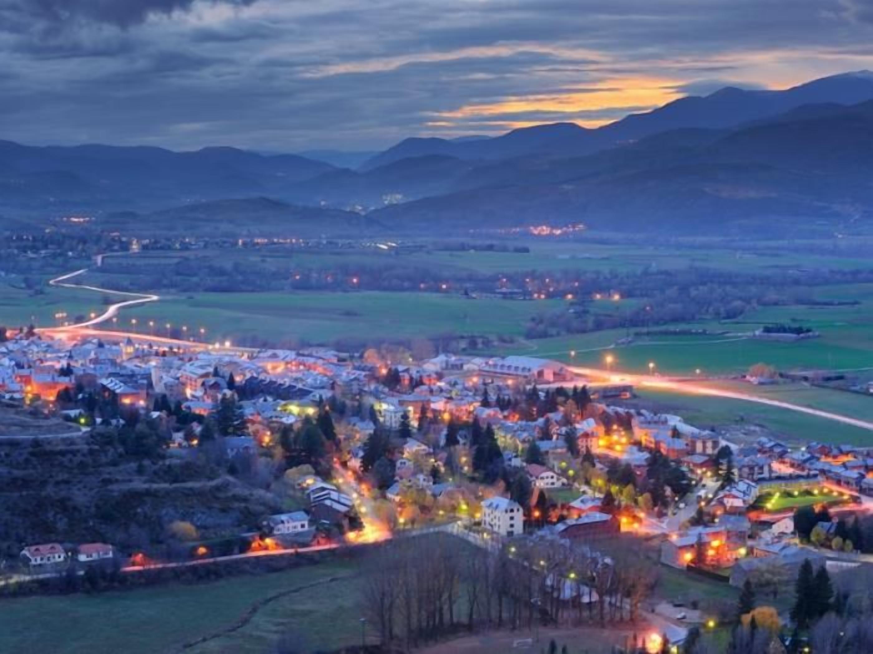 A town with a river, buildings, and a mountain range in the background.