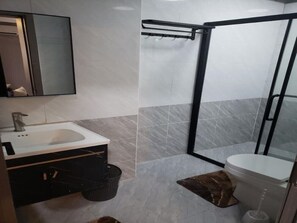 Ein modernes Badezimmer mit einem weißen Waschbecken, einem schwarzen Schrank und einer Duschkabine aus Glas.