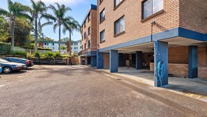 Ein Parkplatz mit Kiesbelag, eine überdachte Garage und ein Gebäude mit Backsteinwänden und blauen Akzenten.