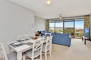 A modern living room with a dining area, large windows, and a view of the outdoors.