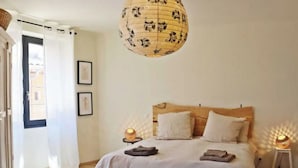 A bedroom with a wooden bed, white bedding, a hanging lantern, and a wooden chest. - The rose house (Buis-les-Baronnies)
