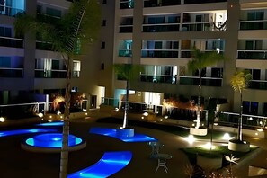 Een hotel met meerdere verdiepingen, met een binnentuin inclusief een waterpartij en zitplekken.