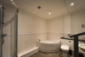 A modern bathroom with a glass-enclosed shower, a freestanding bathtub, a toilet, and a sink.