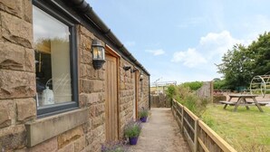Un bâtiment en pierre avec une porte et une fenêtre en bois, un chemin en béton et une clôture en bois.