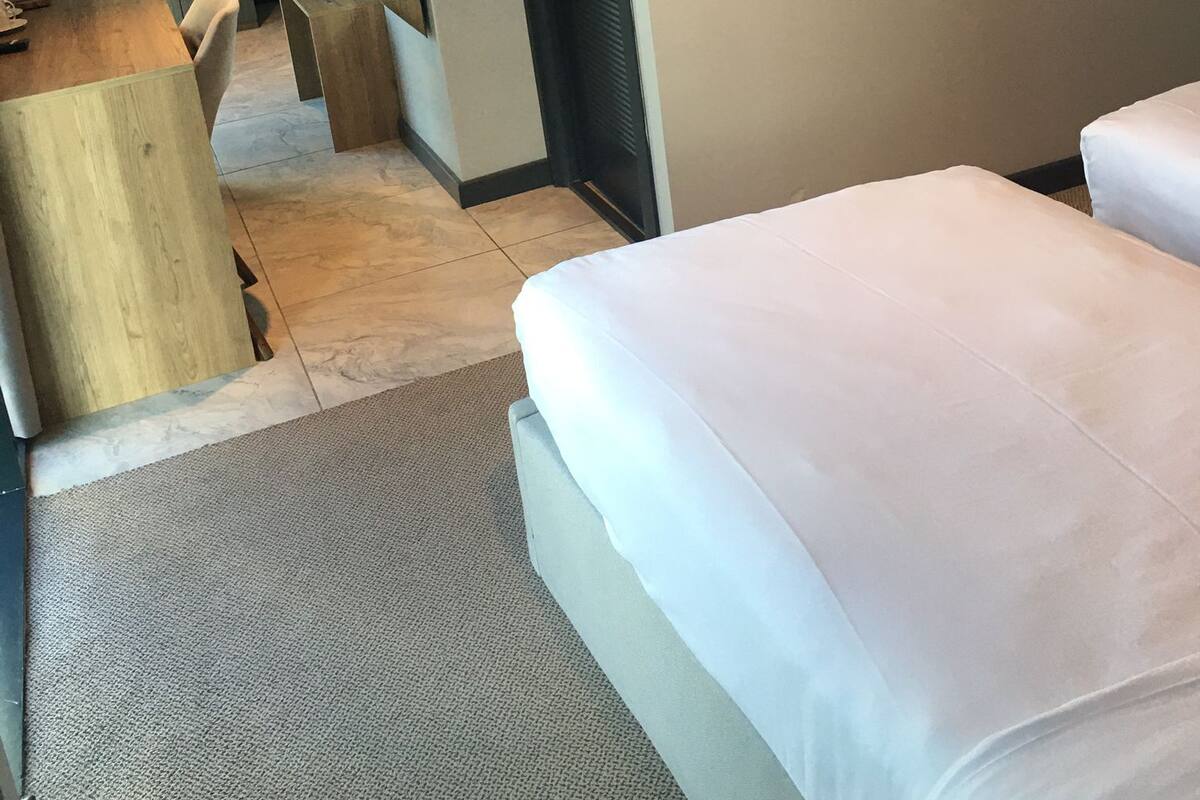A hotel room with a bed, a desk, a chair, a television, and a door.