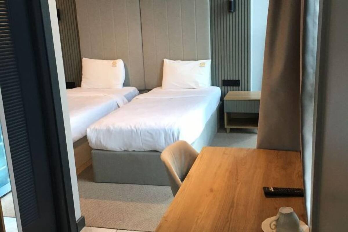 A hotel room with two beds, a wooden table, a chair, and a remote control on the table.