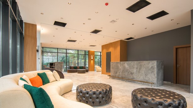 Un vestíbulo amplio con una generosa zona de estar, una recepción y ventanas grandes que ofrecen vistas al exterior.