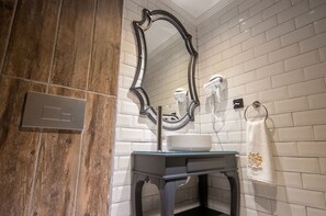 A bathroom with a wooden vanity, a glass sink, a large mirror, and a towel hanging on a hook. - Sherlock Homes Hotels (Istanbul)