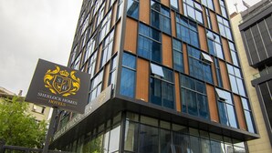 Un edificio moderno de hotel con un letrero de Sherlock Homes Hotels.